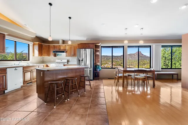 a open kitchen with stainless steel appliances granite countertop a stove top oven a sink a dining table and chairs with wooden floor