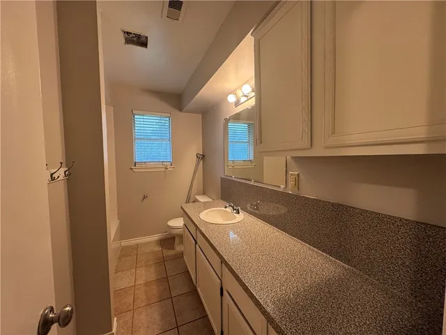 a bathroom with a granite countertop sink a toilet and a mirror