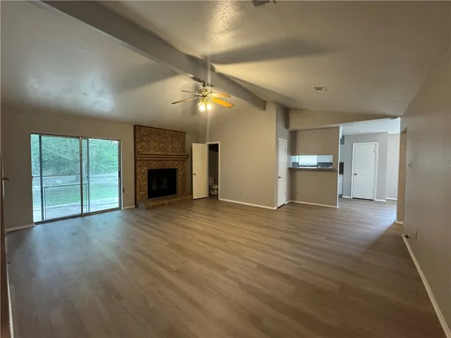 an empty room with wooden floor fireplace and cabinet