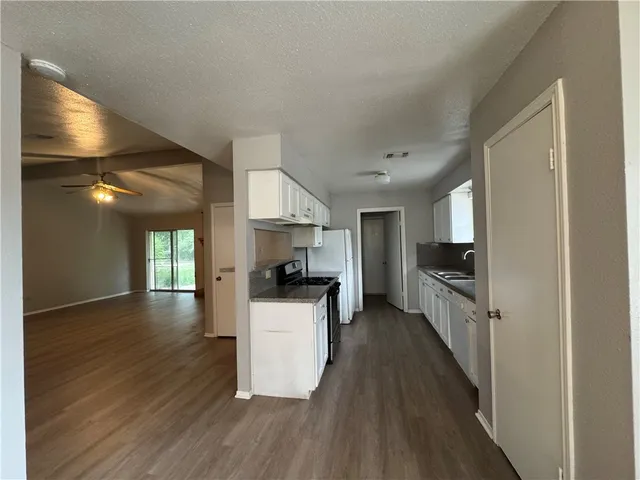 a kitchen with granite countertop a refrigerator a stove top oven a sink dishwasher and wooden floor