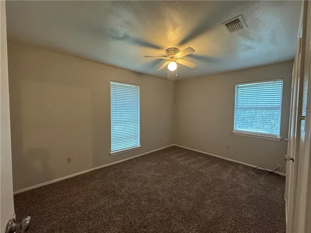 an empty room with windows and fan
