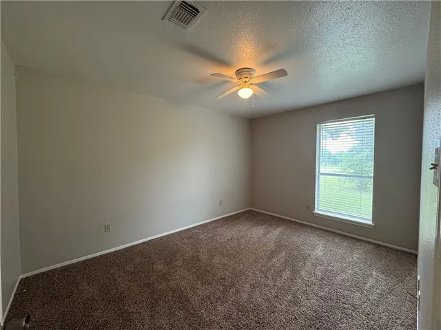 an empty room with a ceiling fan and window