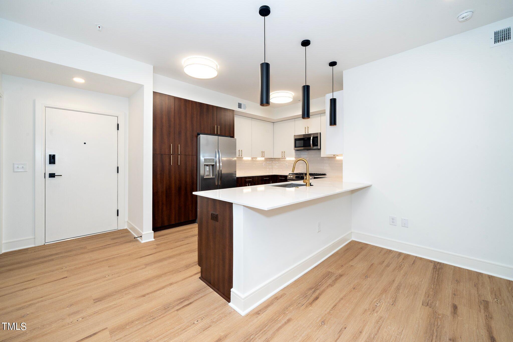 615 West Peace Street, Unit 306 Raleigh, NC 27603 - Photo 7 of 37 a kitchen with wooden floor sink and refrigerator