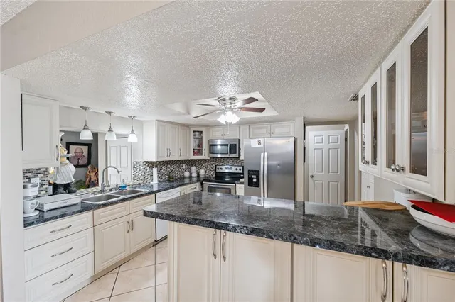 a kitchen with stainless steel appliances granite countertop a sink refrigerator and cabinets