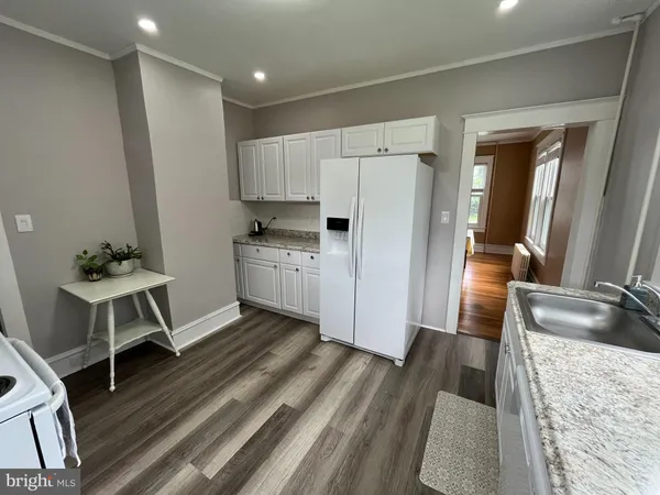a kitchen with a sink appliances and wooden floor