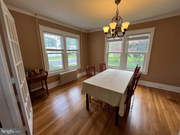 a dining room with wooden floor a chandelier a wooden table and chairs