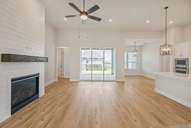 a view of an empty room with wooden floor fireplace and a window