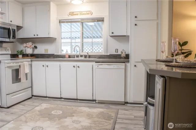 a kitchen with granite countertop white cabinets and white appliances