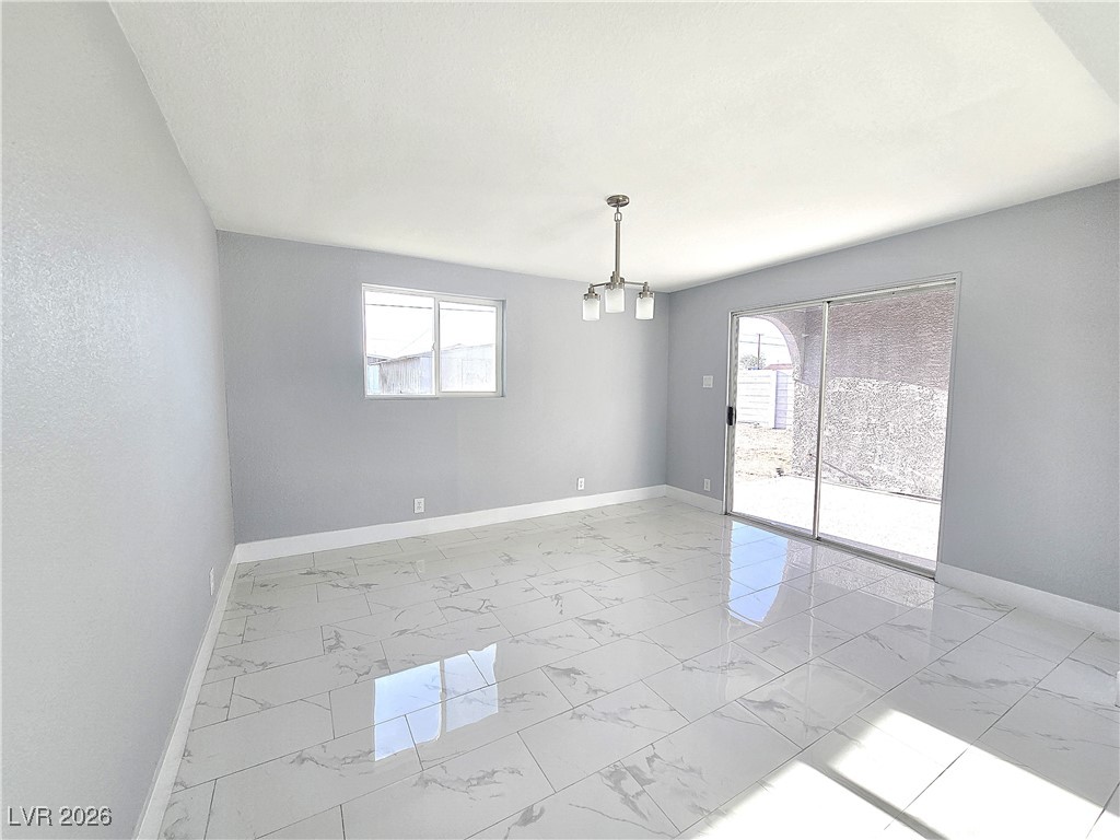 1437 Chestnut Street Henderson, NV 89011 - Photo 3 of 23 Empty room with a chandelier, light marble finish flooring, and healthy amount of natural light