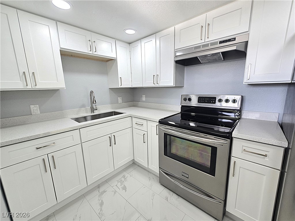 1437 Chestnut Street Henderson, NV 89011 - Photo 5 of 23 Kitchen with stainless steel electric stove, under cabinet range hood, white cabinetry, light marble finish floors, and light stone counters