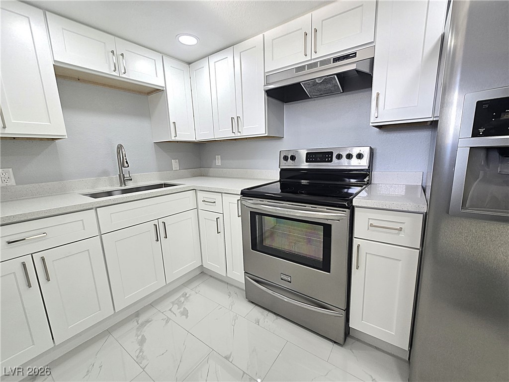 1437 Chestnut Street Henderson, NV 89011 - Photo 6 of 23 Kitchen with stainless steel appliances, under cabinet range hood, white cabinetry, light marble finish floors, and recessed lighting