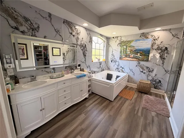 a spacious bathroom with a double vanity sink a mirror a bathtub and next to a window