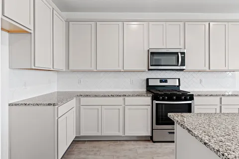a kitchen with white cabinets and stainless steel appliances
