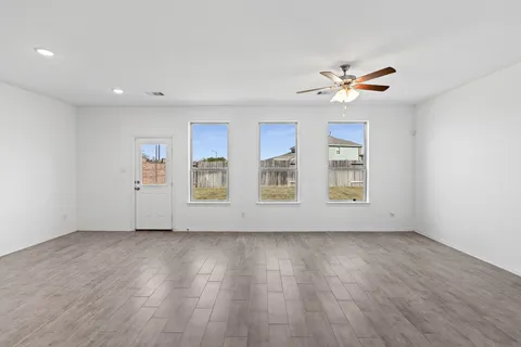 a view of an empty room with a window and wooden floor