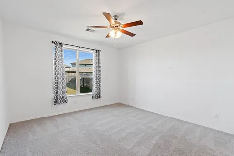 an empty room with a ceiling fan and window