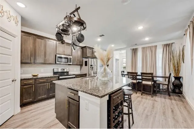 a kitchen with stainless steel appliances granite countertop a stove top oven a sink dishwasher and white cabinets with wooden floor
