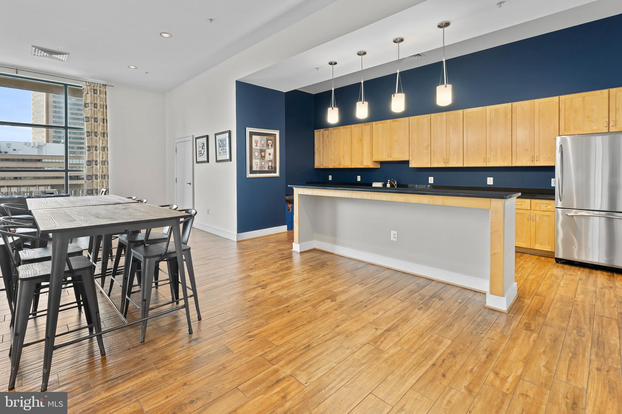 414 Water Street, Unit 2903 Baltimore, MD 21202 - Photo 38 of 46 a kitchen with stainless steel appliances wooden floor dining table chairs and a large window
