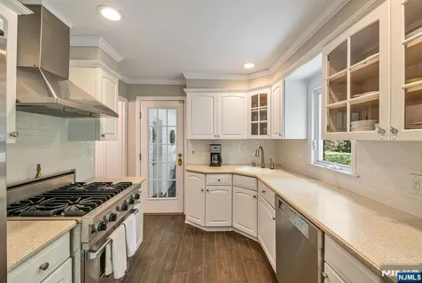 a kitchen with a stove a sink and wooden floor