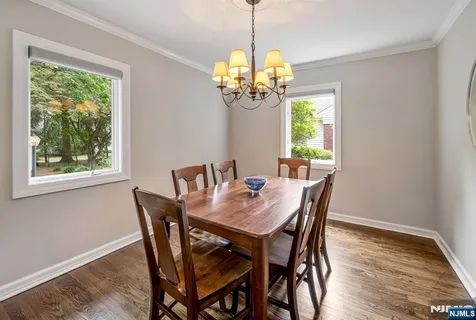 a dining room with wooden floor a chandelier a wooden table and chairs