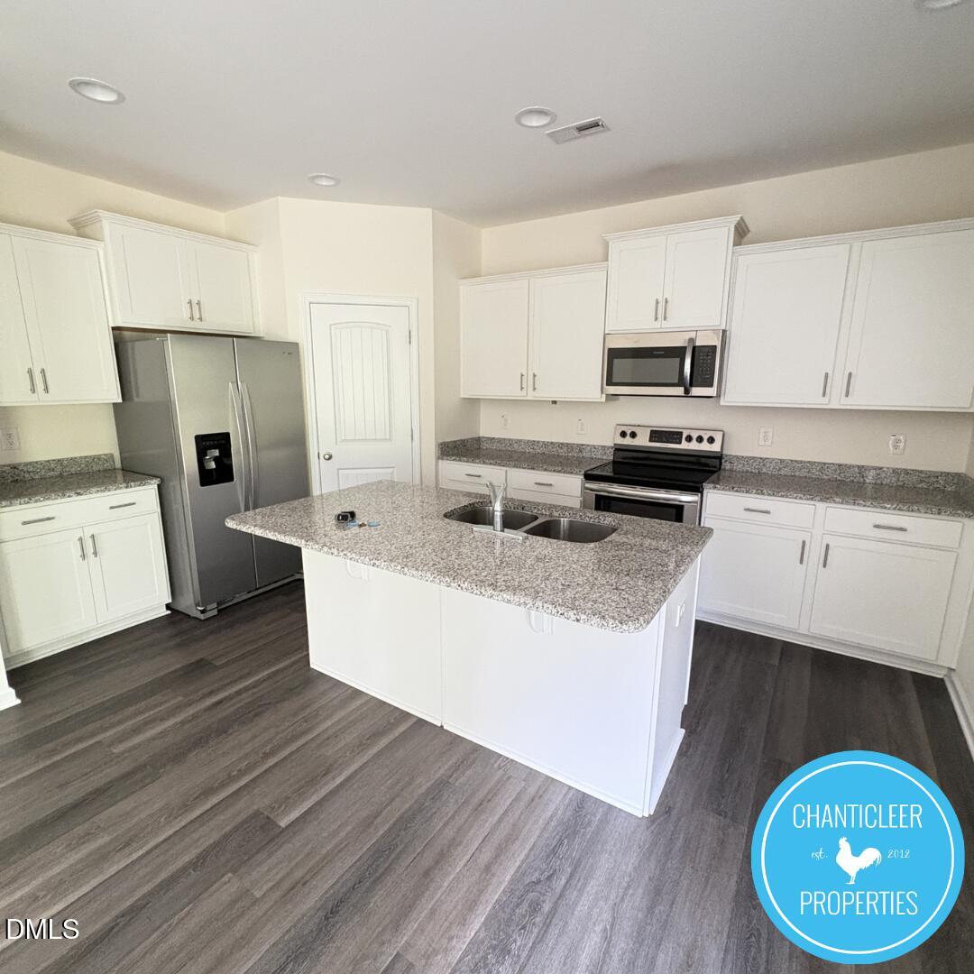 3318 Slippery Elm Drive Raleigh, NC 27610 - Photo 6 of 25 a kitchen with stainless steel appliances a stove a sink a refrigerator and cabinets