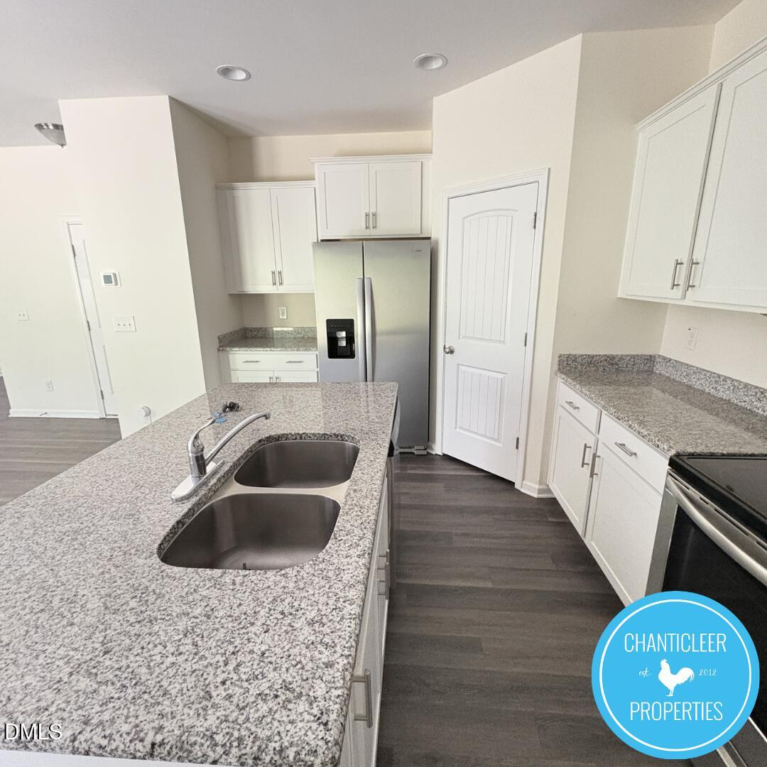3318 Slippery Elm Drive Raleigh, NC 27610 - Photo 7 of 25 a kitchen with stainless steel appliances granite countertop a sink a refrigerator and a stove with wooden floors