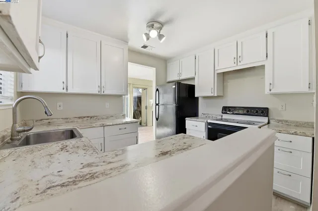 a kitchen with stainless steel appliances granite countertop a sink a stove a refrigerator a center island and cabinets