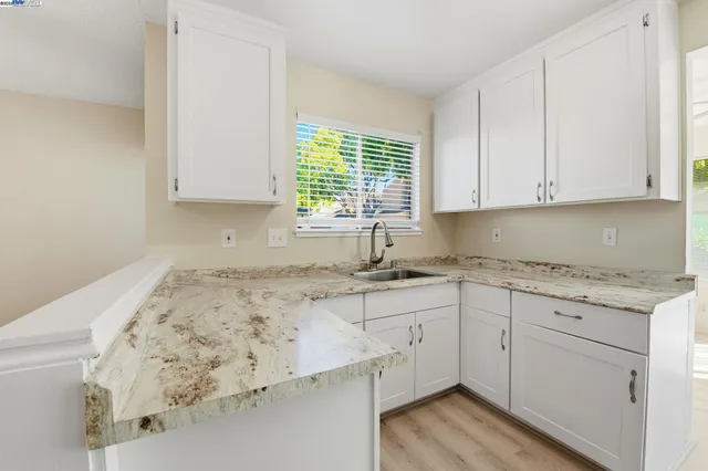 a kitchen with granite countertop white cabinets and a window
