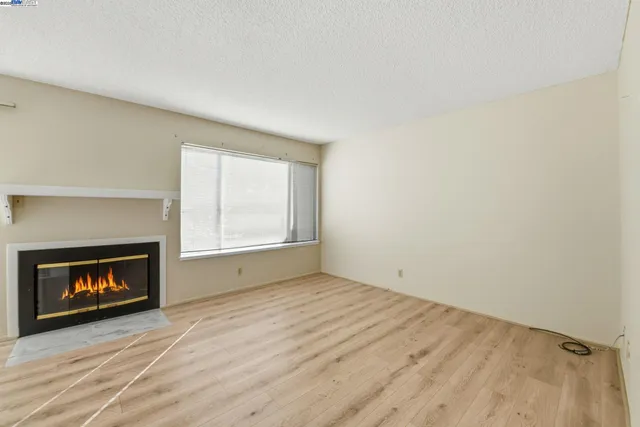 a view of an empty room with a window and fire place