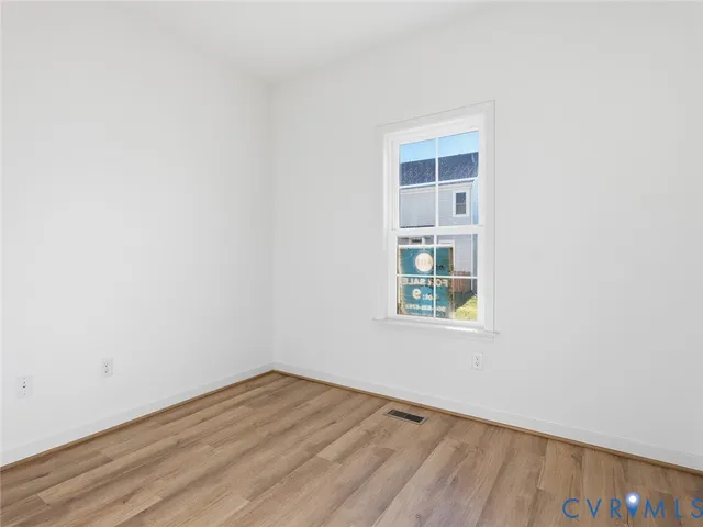 an empty room with a window and wooden floor