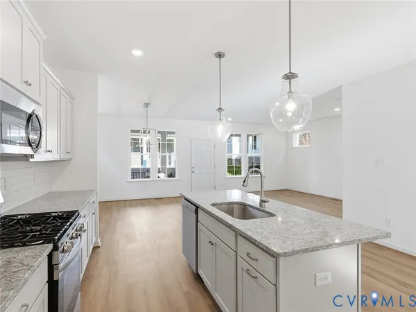 a kitchen with granite countertop a sink a counter space appliances and cabinets