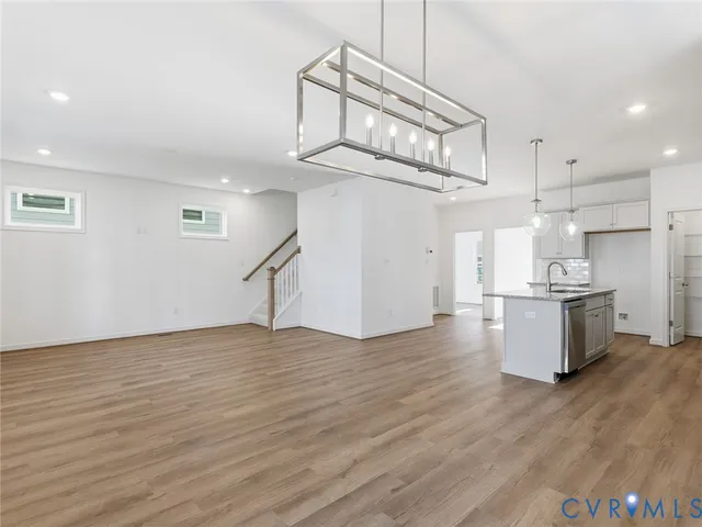 a view of kitchen and empty room with wooden floor