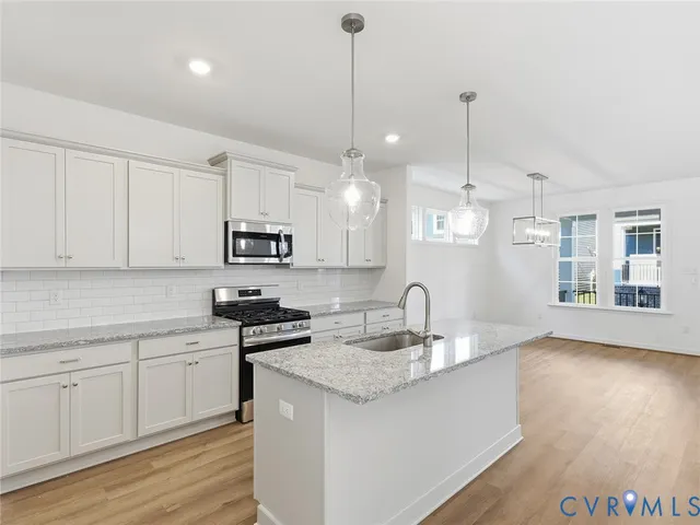 a kitchen with granite countertop a sink a counter space appliances and cabinets