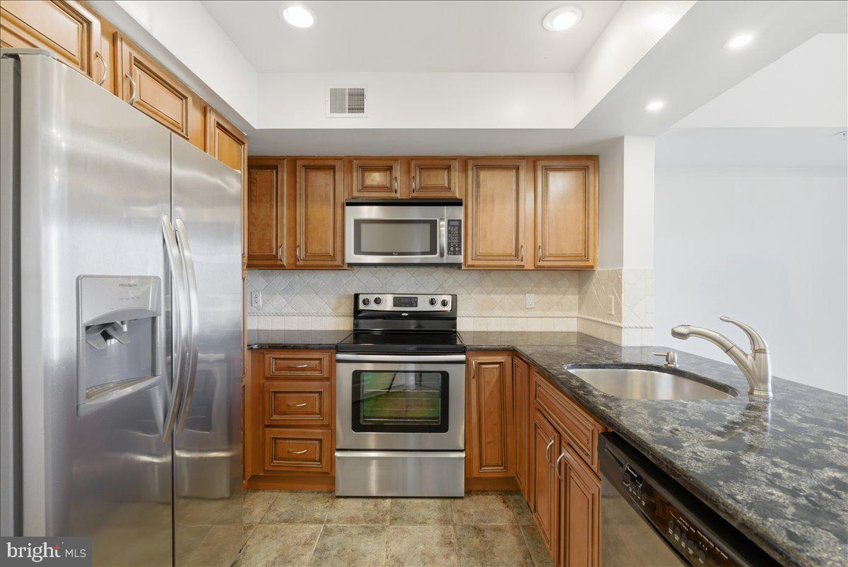 1304 F Garden Wall Circle Reston, VA 20194 - Photo 8 of 23 a kitchen with stainless steel appliances granite countertop a stove a refrigerator and a sink