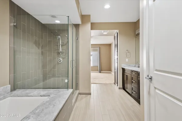 a bathroom with a granite countertop double vanity sink and mirror with bathtub