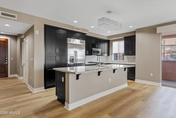 a large kitchen with stainless steel appliances kitchen island a large counter top and a wooden floors