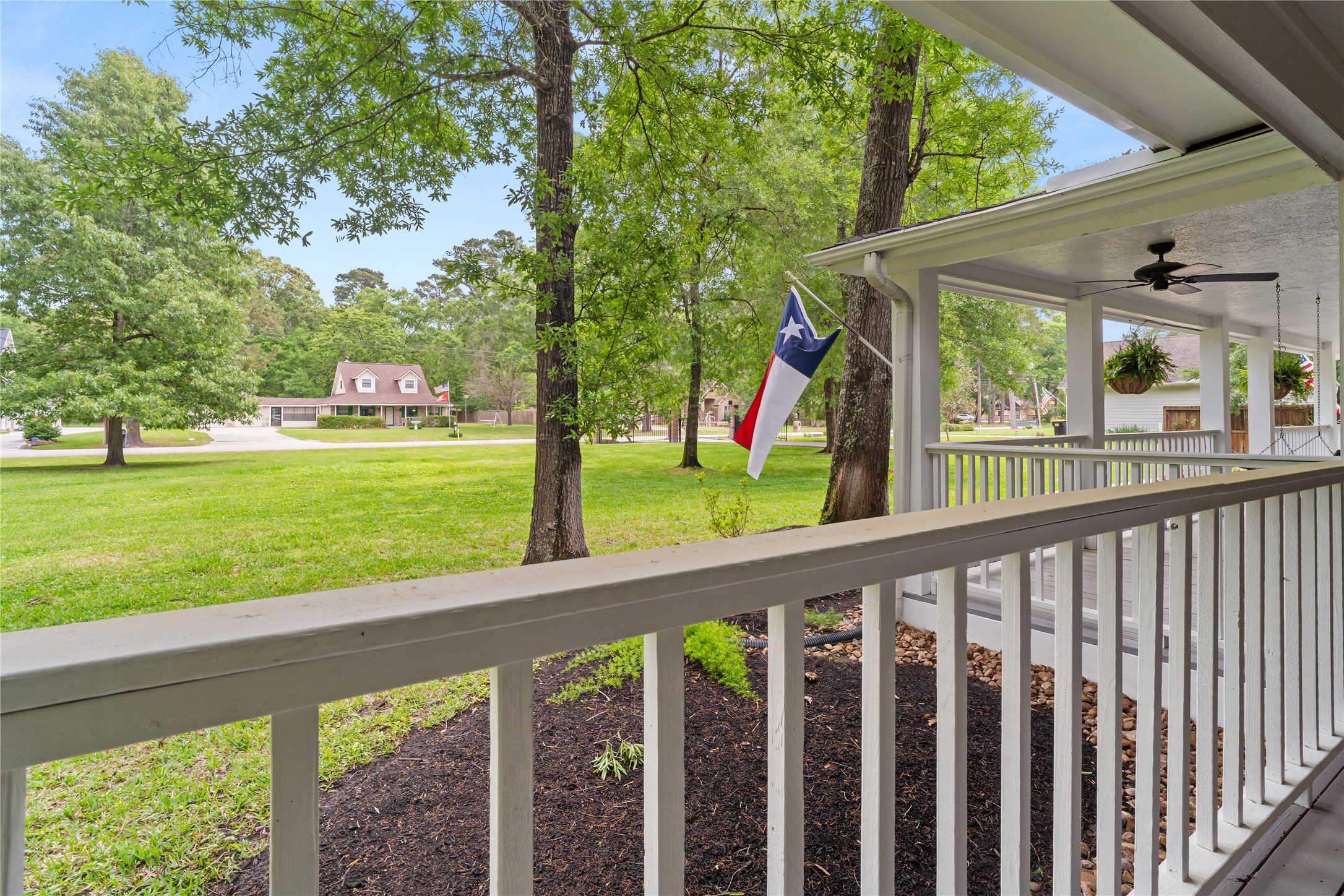 36 Wind River Drive Conroe, TX 77384 - Photo 10 of 45 The charming, covered front porch with a classic design. It features wooden swing chairs, large windows with black shutters, and a serene view of greenery, perfect for relaxation and enjoying the outdoors.