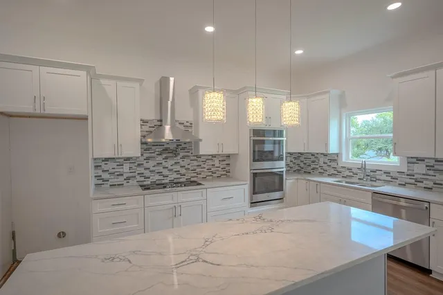a kitchen with stainless steel appliances kitchen island granite countertop a stove and white cabinets
