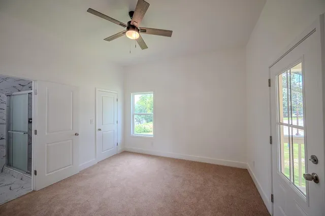an empty room with windows and fan