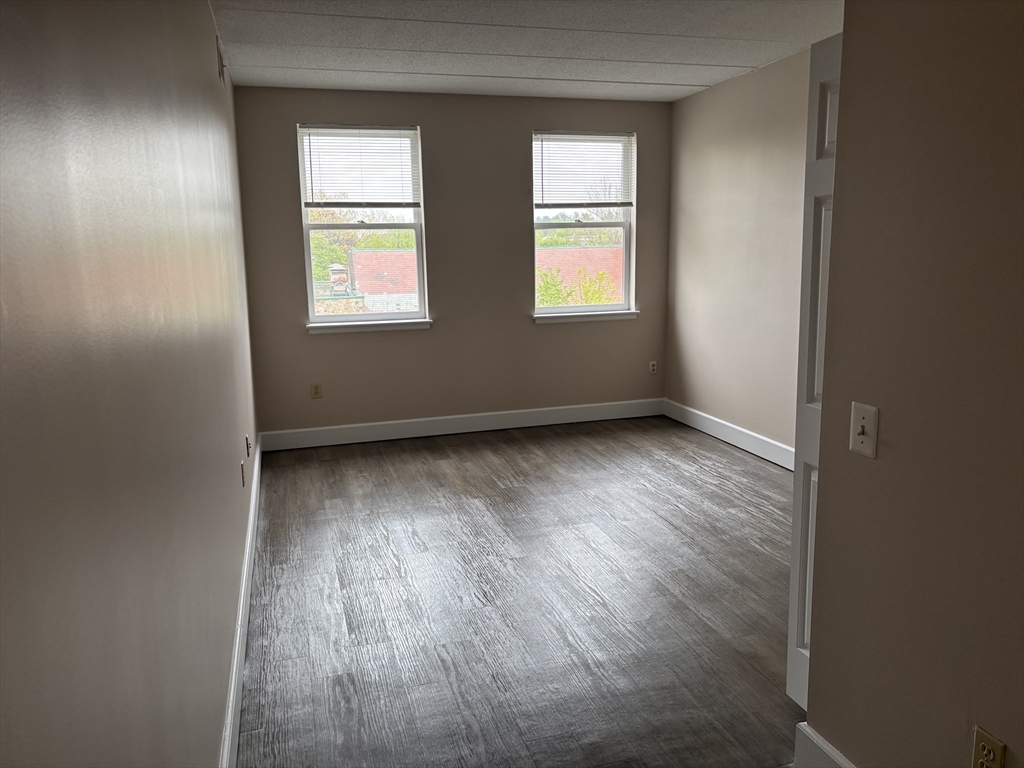 34 Sumner Avenue, Unit 411 Springfield, MA 01108 - Photo 5 of 8 an empty room with wooden floor and windows