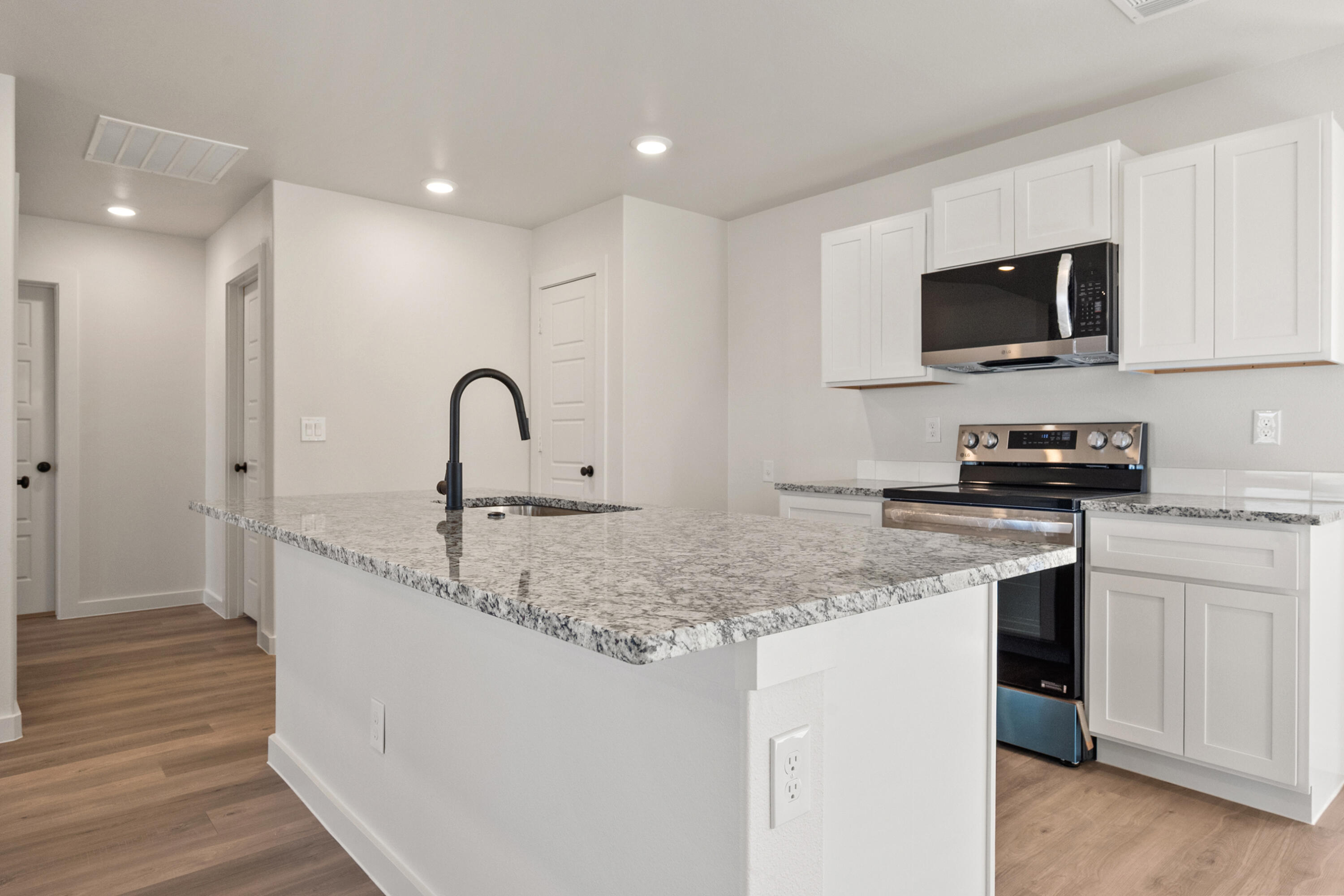 8305 24th Street Lubbock, TX 79407 - Photo 13 of 25 a kitchen with a sink and a stove top oven with wooden floor