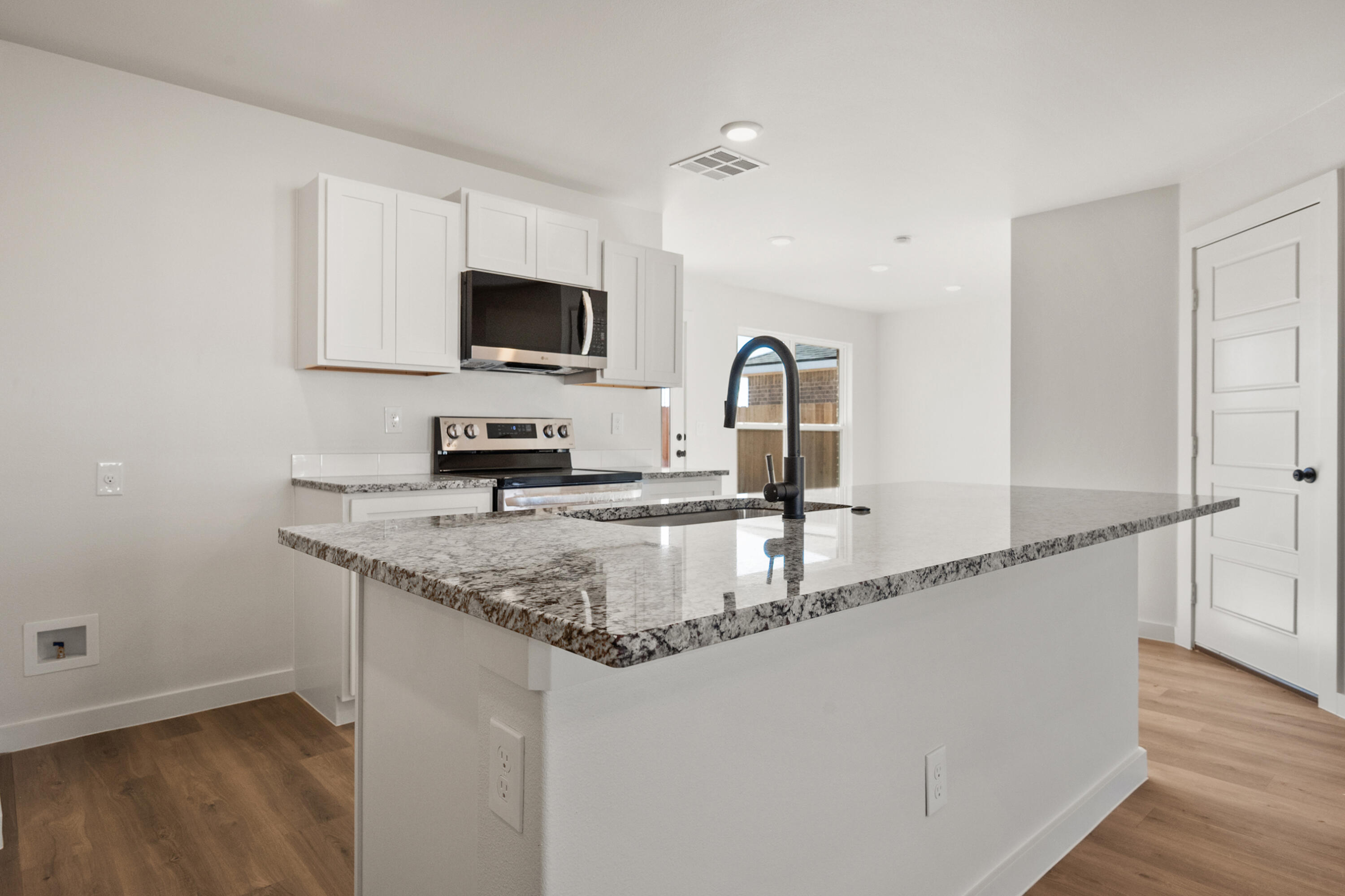 8305 24th Street Lubbock, TX 79407 - Photo 10 of 25 a kitchen with stainless steel appliances granite countertop a sink a microwave a refrigerator and cabinets