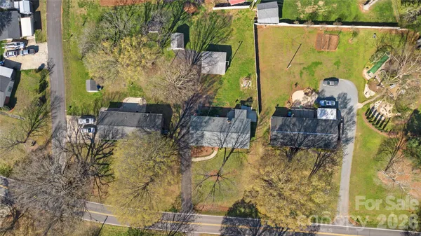 an aerial view of a house with swimming pool and large trees