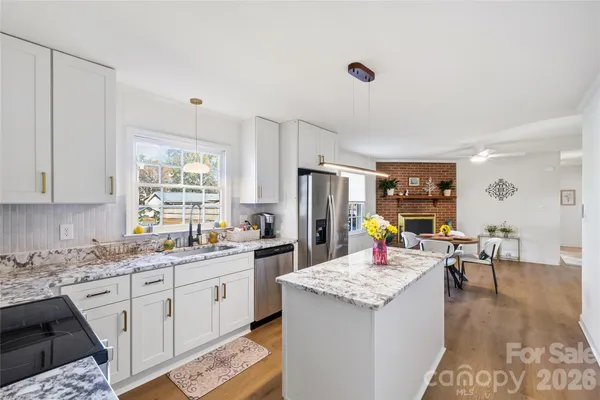a kitchen that has a lot of white cabinets and stainless steel appliances