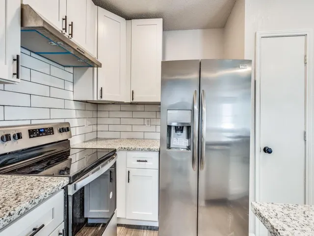 an open kitchen with granite countertop a sink and white cabinets