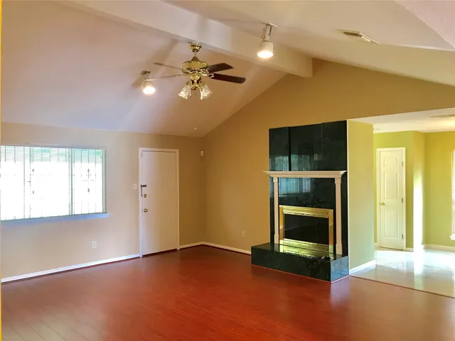 a view of empty room with wooden floor and fan