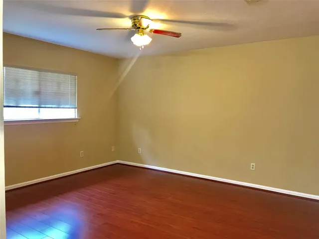 en empty room with wooden floor and fan
