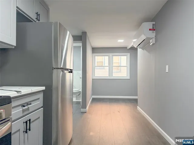 a view of a kitchen with a fridge and wooden floor