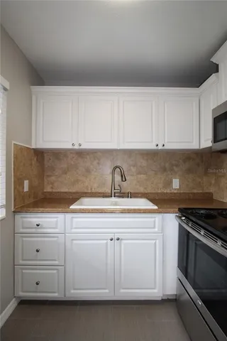 a kitchen with white cabinets and sink