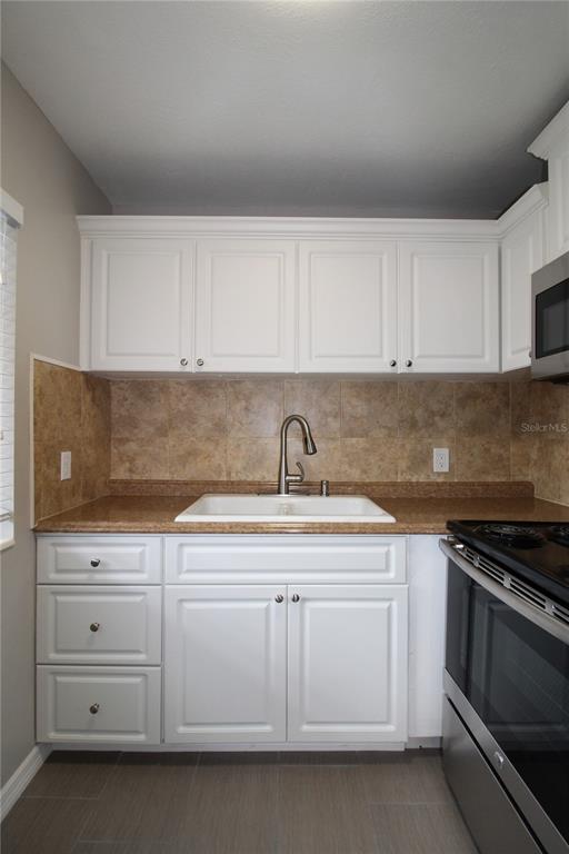 3001 Bee Ridge Road, Unit 111 Sarasota, FL 34239 - Photo 2 of 20 a kitchen with white cabinets and sink