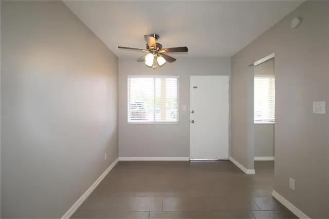 an empty room with windows and fan